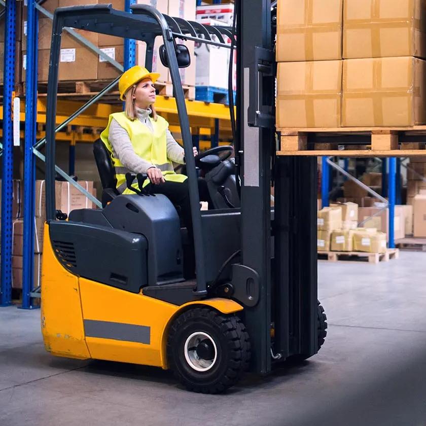 Young workers working together. Woman forklift driver and a man in a warehouse.